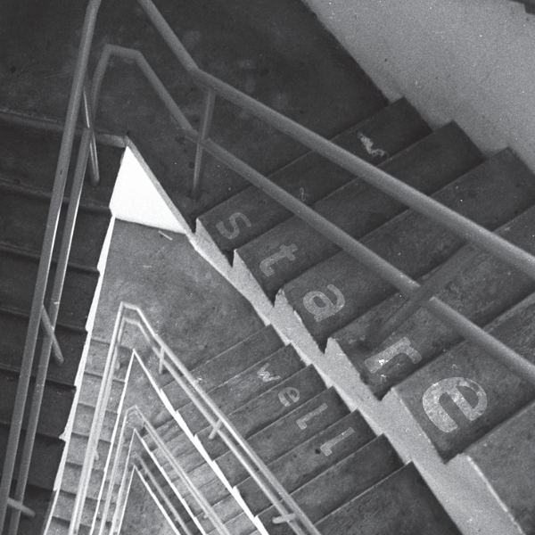 Background is a black and white photograph looking down into a triangular stairwell. The words stare (s-t-a-r-e) well are superimposed on the stairs; one letter per stair.